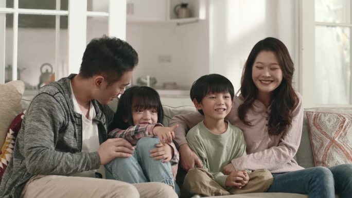 年轻的亚洲家庭在家里一起看电视