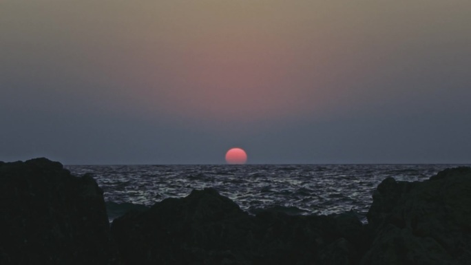 橙色的天空和日落在灰色的大海或海洋的平静波浪上。宁静、禅宗般的电影场景。慢动作视频。