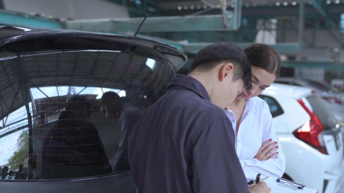 一位男机械师和一位女顾客在讨论对她的汽车进行的维修。