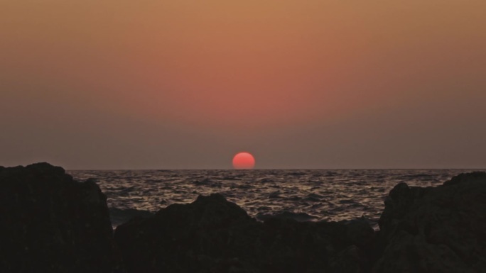 橙色的天空和日落在灰色的大海或海洋的平静波浪上。宁静、禅宗般的电影场景。慢动作视频。