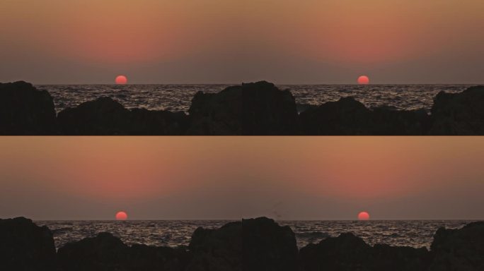 橙色的天空和日落在灰色的大海或海洋的平静波浪上。宁静、禅宗般的电影场景。慢动作视频。