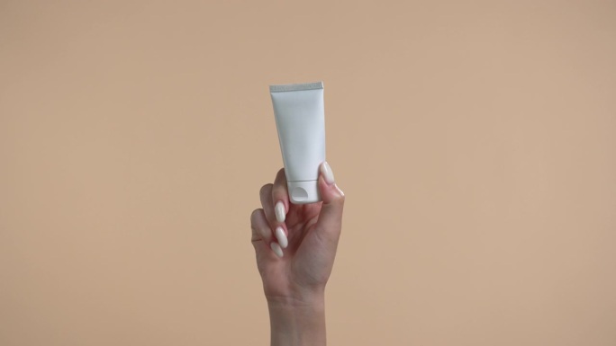一位女士拿着米色背景的美容产品