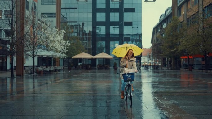 打着黄伞的年轻女子在雨中骑自行车