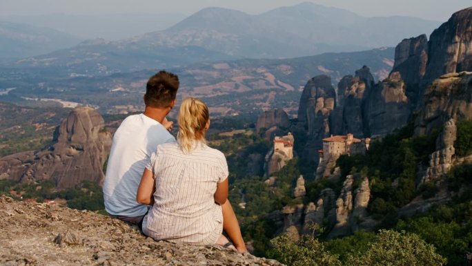 一对夫妇坐在岩石上探索迈泰奥拉修道院
