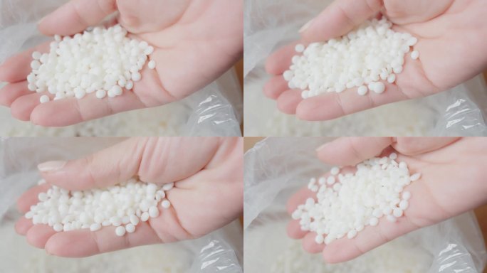手握小白色大豆蜡颗粒，适用于工业或手工艺。