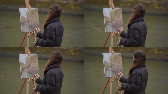 一个女人在塞纳河附近画画。一位富有创造力的女艺术家站在巴黎的画架旁，用画笔作画。女艺术家，艺术销售，