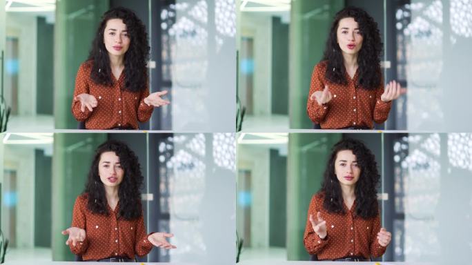 摄像头的观点。一位自信的女商人坐在现代办公室的办公桌前，通过视频连接进行交谈。