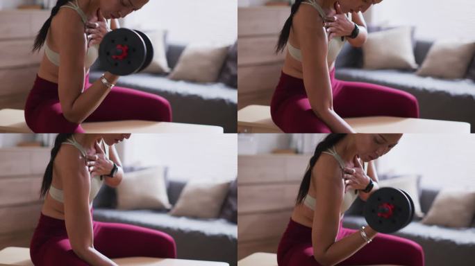 肌肉发达的年轻女子在家锻炼，用哑铃训练。健美肌肉女运动员保持健康，在家训练
