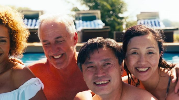 暑假期间，一群不同文化背景的老人朋友在室外泳池里放松的照片