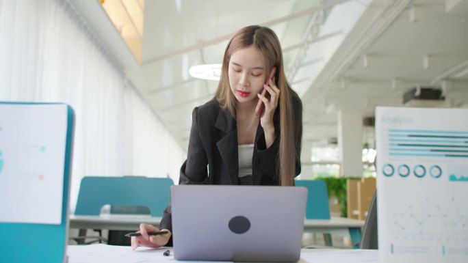 在办公室用手提电话处理项目文书工作的女商人