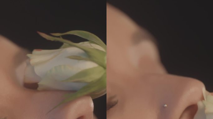 性感的女人用红色的口红黑色的背景工作室拍摄，摆姿势与单一的白玫瑰和调情的相机