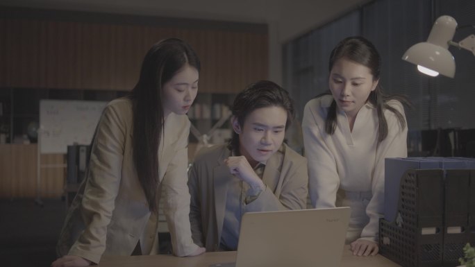夜晚办公室三个人在电脑前讨论项目 创业