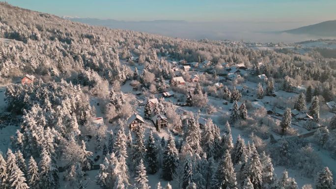 阳光普照、白雪覆盖的山村山间针叶林无人机拍摄