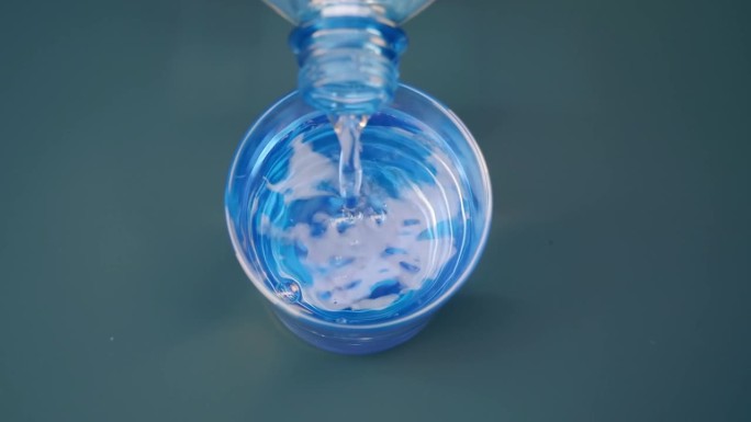 干净的、闪闪发光的淡水从塑料瓶里倒进玻璃杯里