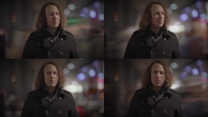一个长卷发的男人站在午夜活动的黑暗中