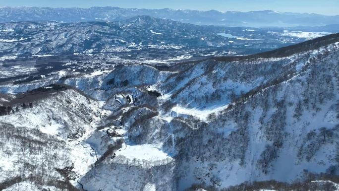 无人机从白雪皑皑的山顶上拍摄，镜头向前推进，向上平移。日本火山myōkō是位于名古屋人山国立公园地区