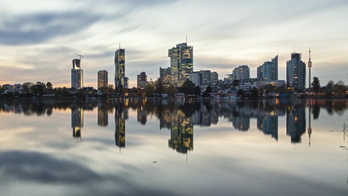 维也纳商业区的多瑙城(Donaustadt)的昼夜渐变天际线。平静的湖面上的倒影。