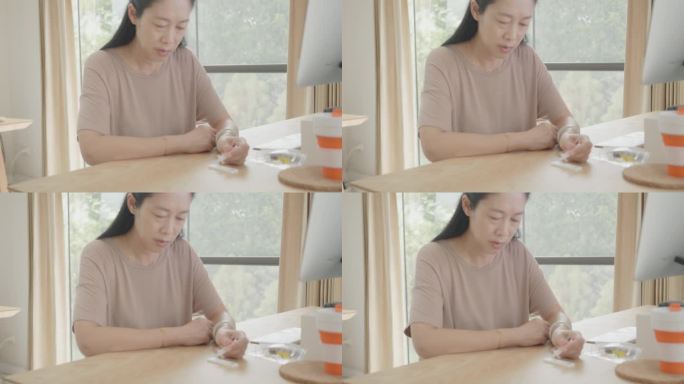 一名患有糖尿病的东南亚妇女在家中使用血糖自测仪检查血糖