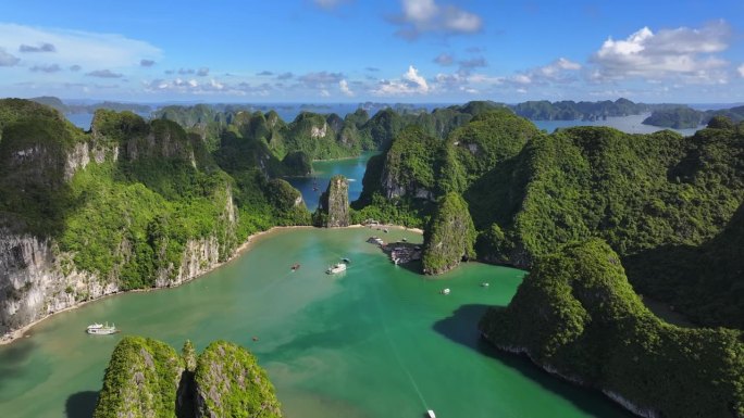 在越南北部下龙湾的海上，航拍无人机拍摄的观光船与岩石山的淡蓝色天空
