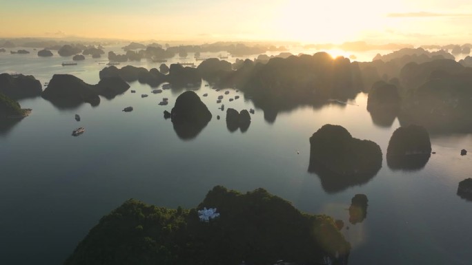 在越南北部下龙湾的海上，航拍无人机拍摄的观光船与岩石山的日出景象