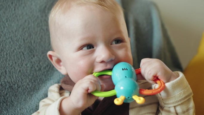 可爱的男孩咬蝴蝶形状的出牙玩具