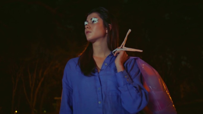 小女孩在夜晚的灯笼灯光下摆出清扫公园的姿势。长睫毛的女人