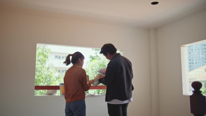年轻夫妇在装修家时选择墙壁的合适颜色。