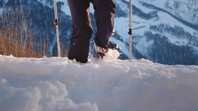 登山鞋在冬季徒步时在雪地上行走或奔跑。北欧拐杖。一个老妇人的腿