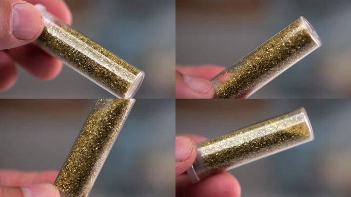 一个男人的手指小心地转动着一个玻璃小瓶，在一个微距的慢动作镜头中捕捉到闪闪发光的颗粒。