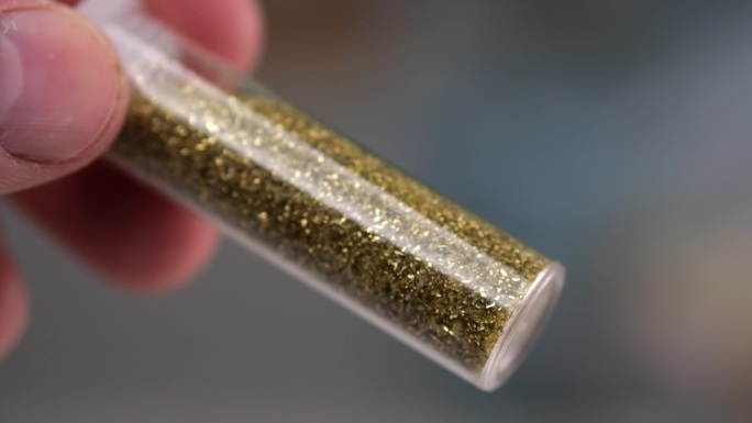 一个男人的手旋转着一个装满闪闪发光的小点的玻璃罐子，慢镜头检查质量。