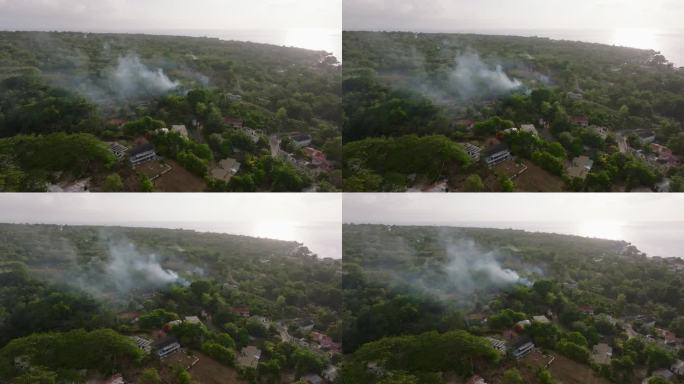 鸟瞰图:烟雾笼罩着郁郁葱葱的牙买加乡村，远处的海岸线在朦胧的天空下。展示了加勒比海乡村的宁静之美