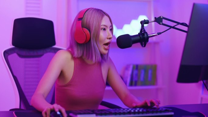 亚洲漂亮的电子竞技女性玩家在电脑上玩在线视频游戏。有吸引力的年轻女孩游戏玩家感到快乐，享受科技直播，