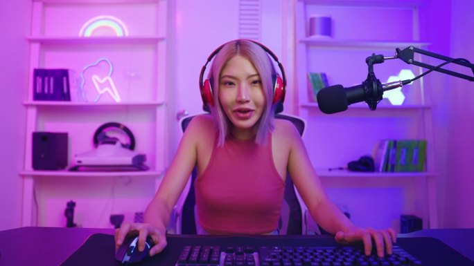亚洲漂亮的电子竞技女性玩家在电脑上玩在线视频游戏。有吸引力的年轻女孩游戏玩家感到快乐，享受科技直播，