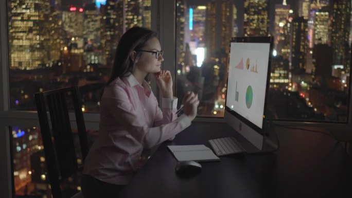 在办公室用电脑工作到很晚的女商人。分析公司的图表和统计。成功，金融，财富，成长。