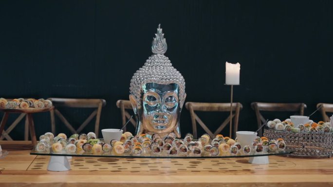 优雅的寿司桌布置，配有装饰性的佛像中心和烛光照明。