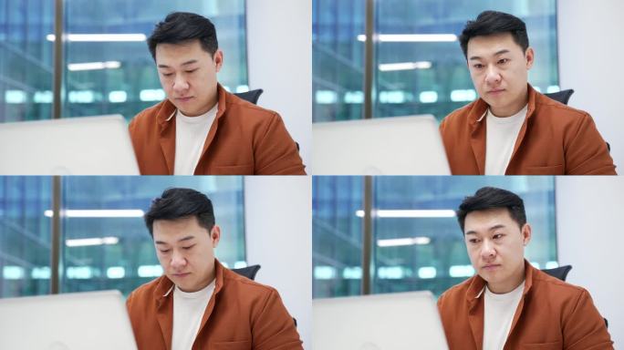 自信的亚洲商人在商务办公室的工作场所坐着，正在用笔记本电脑打字。