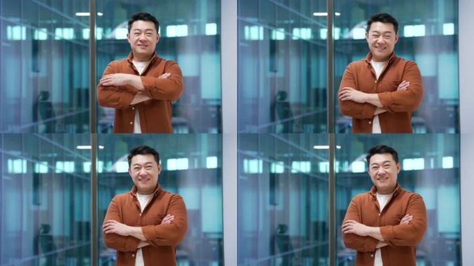 一位快乐的亚洲商人在现代商务办公室的工作场所双臂交叉站立。