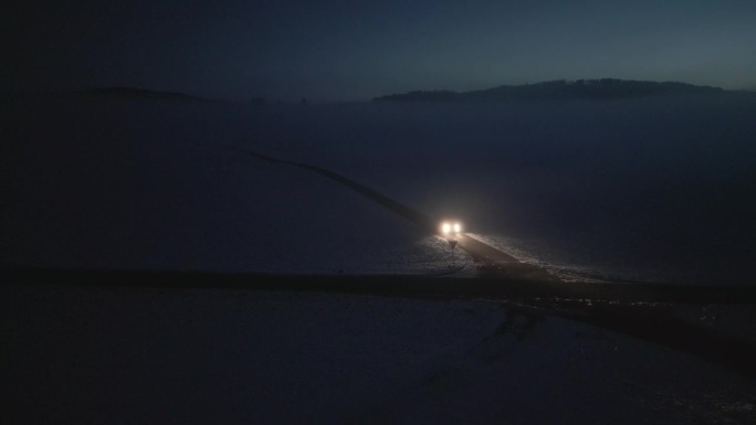 汽车在乡村冬季道路上行驶并在夜间转弯的跟踪镜头