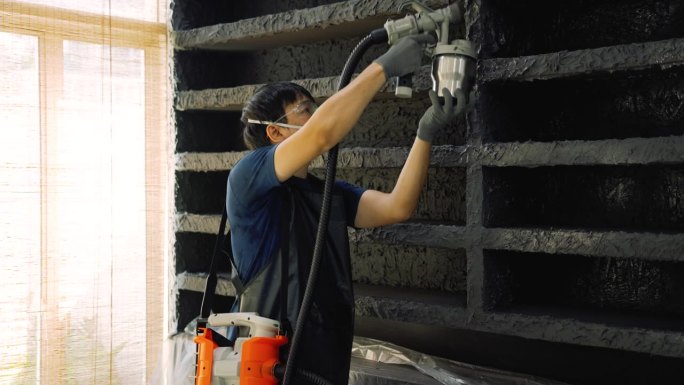 建筑工人正在使用电动喷漆机喷涂油漆。