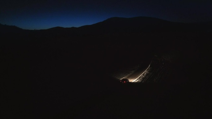 汽车在冬季森林道路上夜间行驶的空中跟踪镜头
