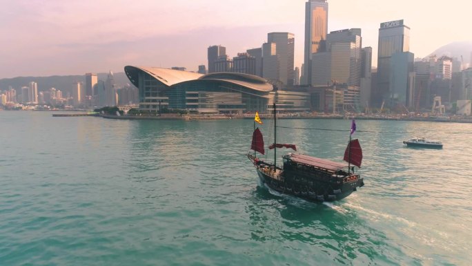 中国香港 - 2025年2月2日：传统船只在现代天际线附近航行。