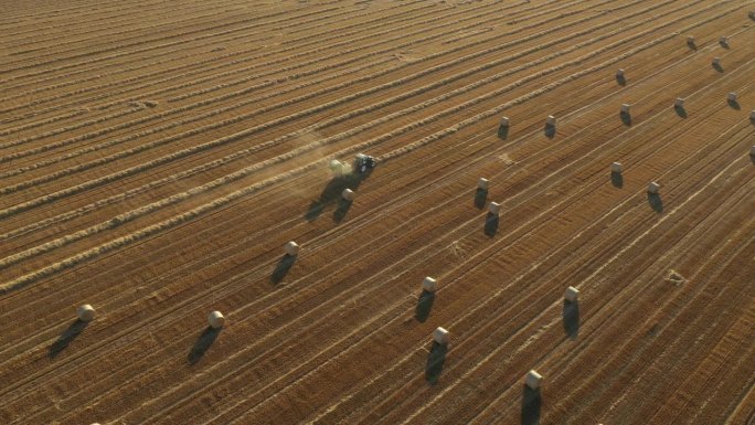 收割后的田野上，拖拉机牵引的打包机在空中俯瞰收集稻草。