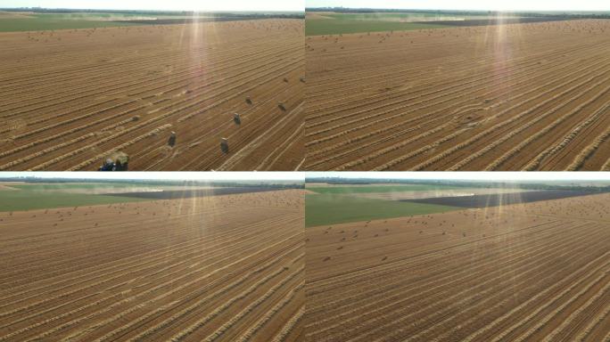收割后的田野上，拖拉机牵引的打包机在收集稻草的鸟瞰图。