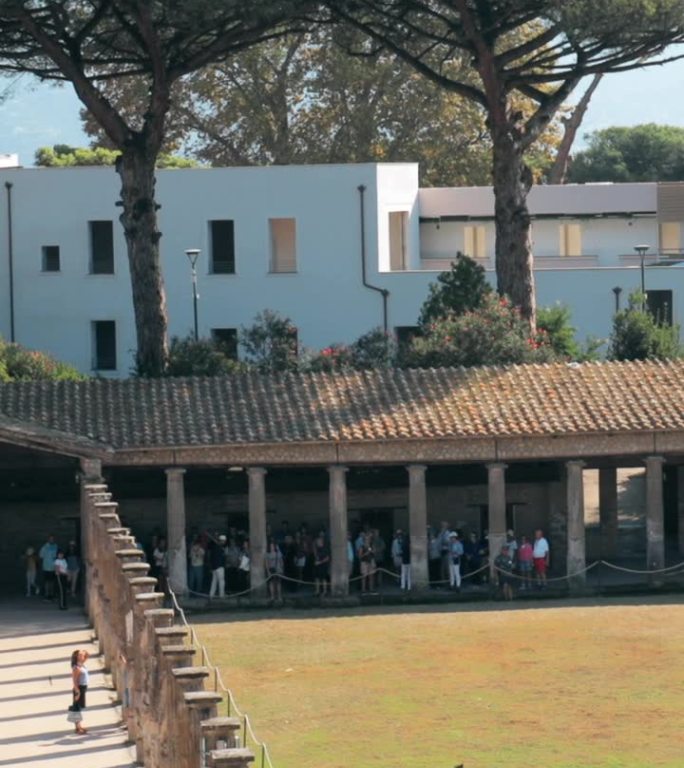 庞贝，意大利。游客在阳光明媚的日子里走近古老建筑四柱廊的遗迹。联合国教科文组织世界遗产。