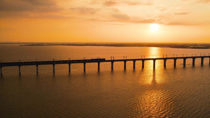 夕阳下运煤货运火车行驶在大桥上