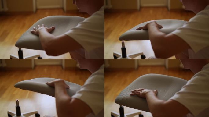 特写镜头：男子在家组装符合人体工程学的电脑椅，触摸软垫座椅，检查质量和舒适度，家具组装，家居改善，D