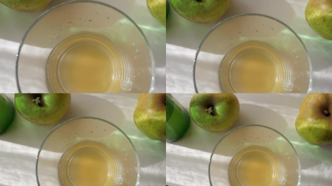 新鲜倒入玻璃杯中的天然苹果酒，周围环绕着苹果。