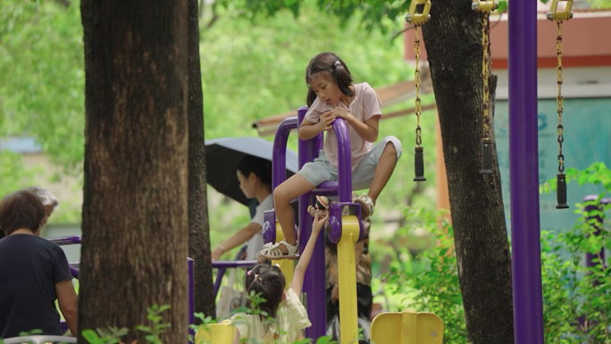 老年人带小孩素材 小孩在广场健身器材上玩
