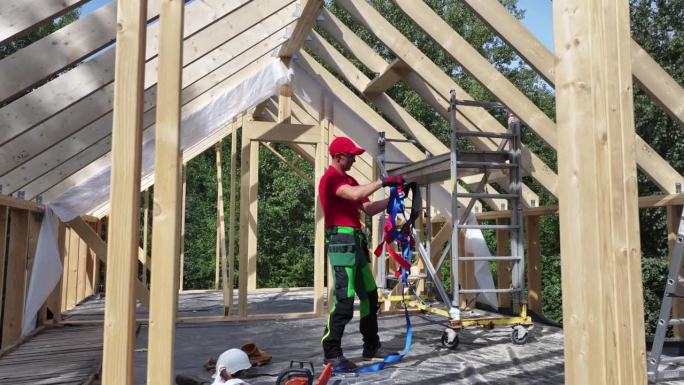 建筑工人在白天的住宅区屋顶上工作时使用安全带。