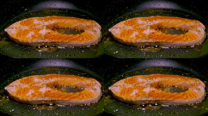 三文鱼正在黑色铸铁锅中与香草、胡椒和百里香一起煎炸。